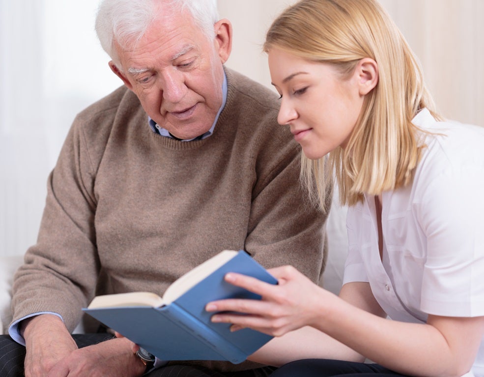 Senior reading with caregiver